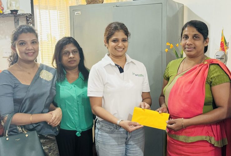 A photo of the president of the HCK PPA surrounded by a few PPA committee members and the staff members of Wathuliyadda Primary School, handing over the donation to the Principal of Whathuliyadda Primary School.