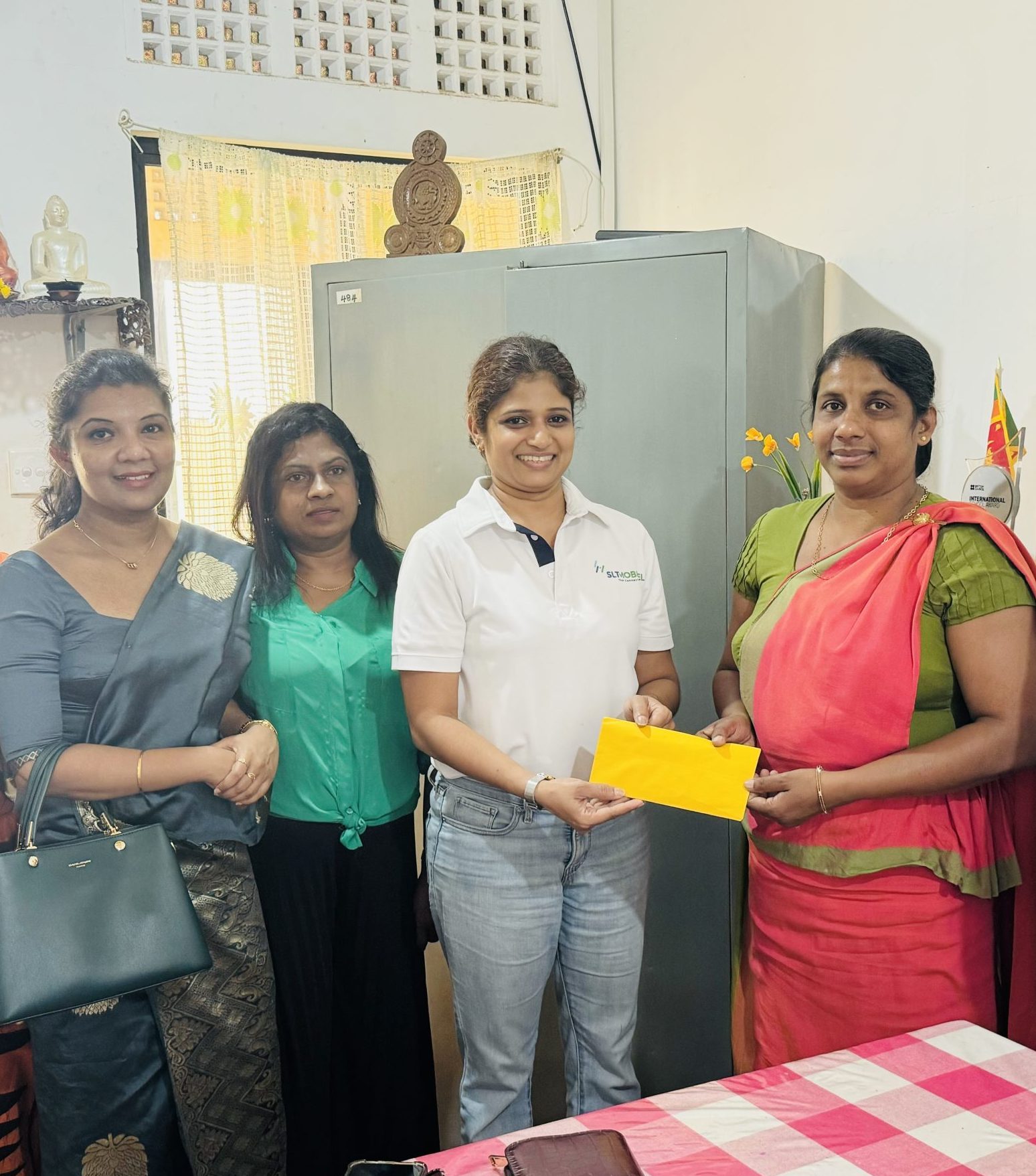 A photo of the president of the HCK PPA surrounded by a few PPA committee members and the staff members of Wathuliyadda Primary School, handing over the donation to the Principal of Whathuliyadda Primary School.